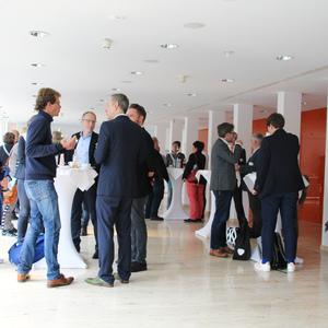 Gruppengespräch auf einer Networking-Veranstaltung in einem modernen Raum mit Stehtischen und geselligem Austausch.