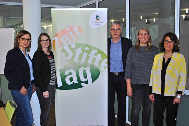 Gruppenfoto von fünf Personen vor einem Banner mit dem Text „Zeit Stifte Tag“ und dem Logo der Freiwilligen-Agentur Münster.